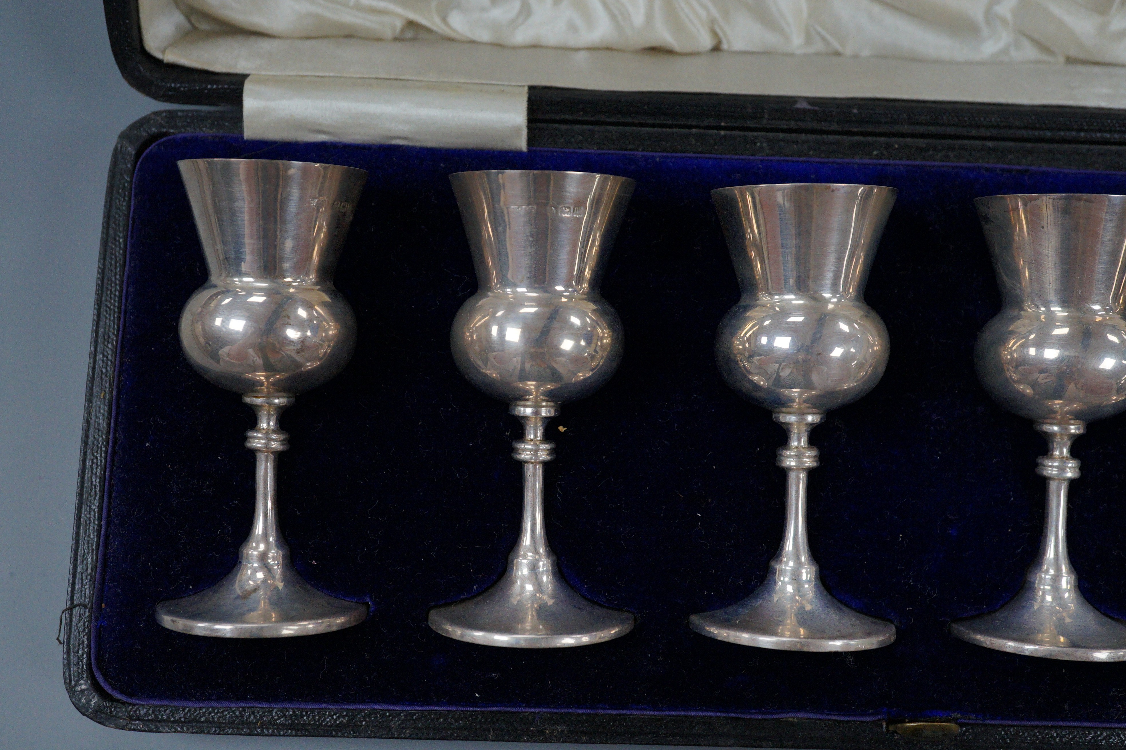 A cased set of six George V silver thistle shaped pedestal tots, E.S. Barnsley & Co, Birmingham,1911, 83mm.